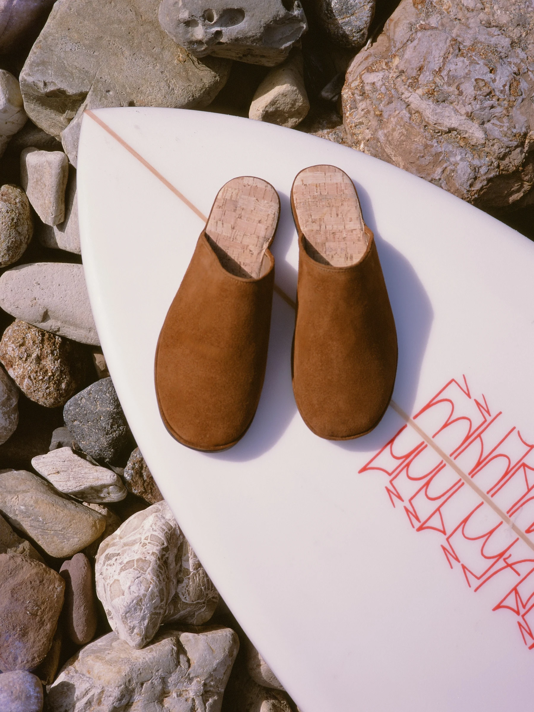 The Dume in Tobacco Suede on a surfboard