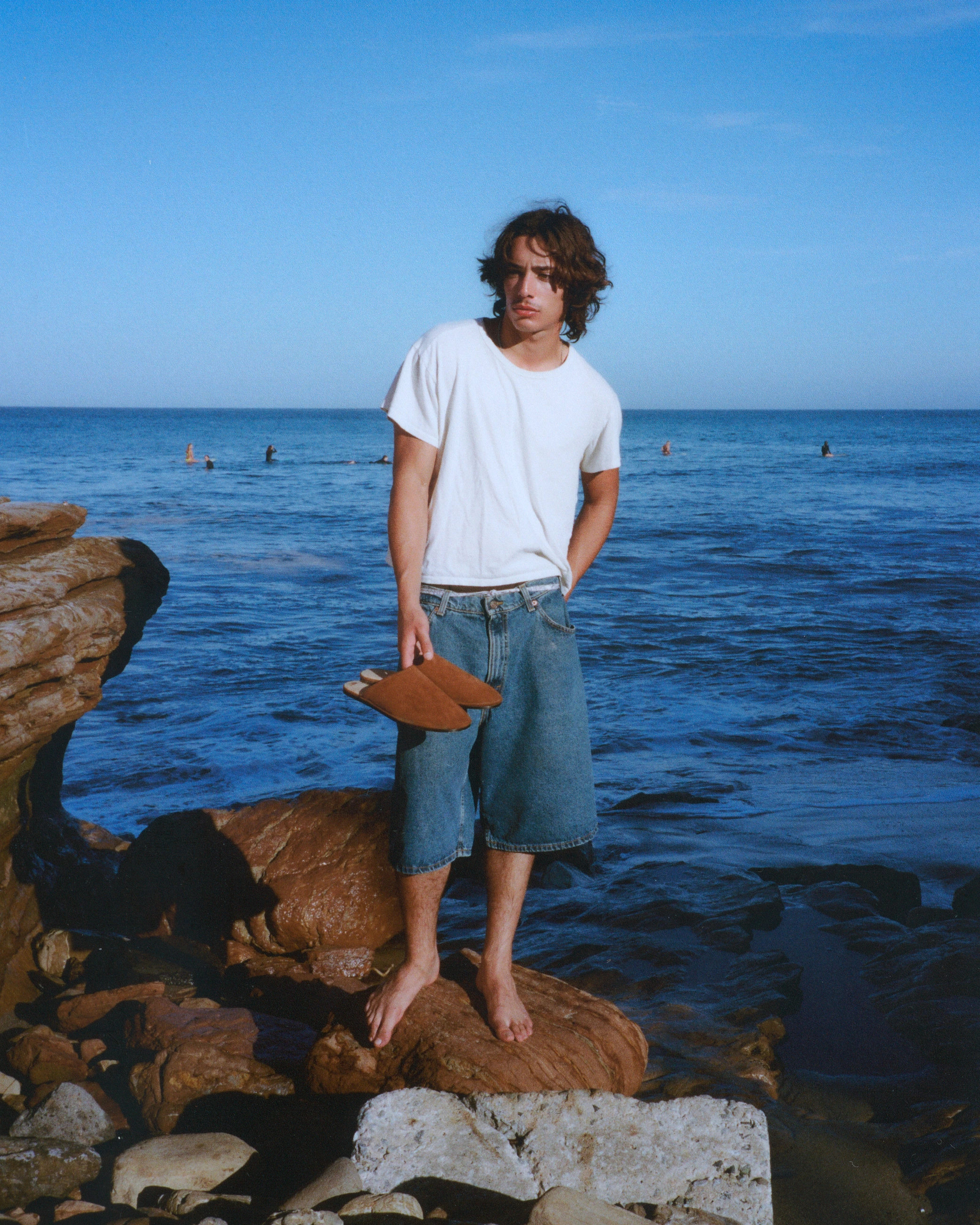 Beachwood portrait on the Malibu coast, holding Tobacco Suede mules